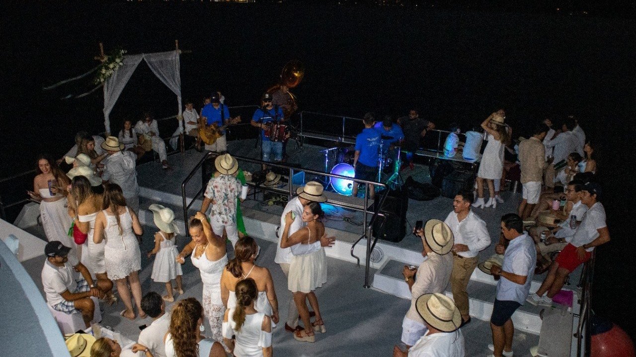 Evento de noche en la cubierta de un catamarán para 150 invitados en Puerto Vallarta, con banda en vivo y decoración en blanco